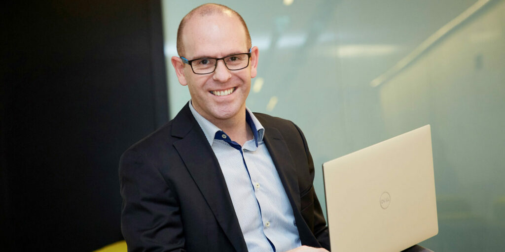 Christian Schauperl mit Laptop in Businesskleidung